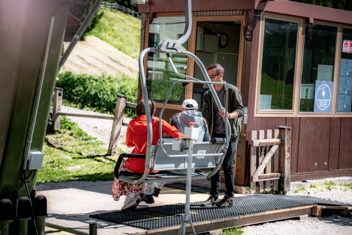 Seggiolino della seggiovia Sole una signora e ed un bambino sono seduti sul seggiolino mentre l'uomo sta per salire